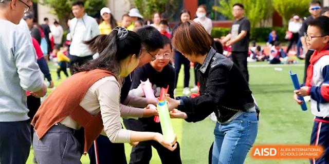 Students participate in a team-building exercise by passing colorful tubes during an outdoor event at Wuhan Guanggu Future School.