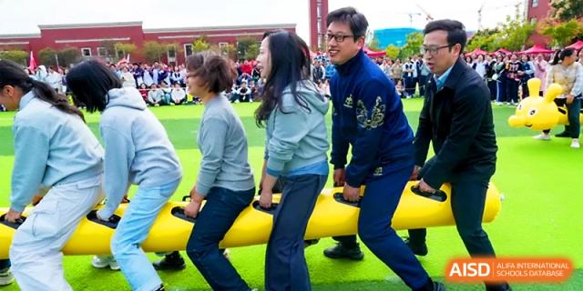 Teachers and staff participate in a team race on a long yellow inflatable during a sports festival at Wuhan Guanggu Future School.