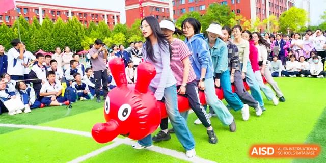 Students laugh while racing on large, red inflatable bouncy toys during a fun field day at Wuhan Guanggu Future School.