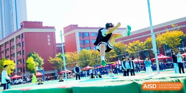 An athlete in mid-air performs a long jump into a sandpit during an outdoor sports meet at Wuhan Guanggu Future School.