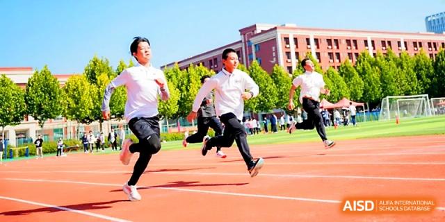 Three male students race toward the finish line during a competitive track event on campus at Wuhan Guanggu Future School.