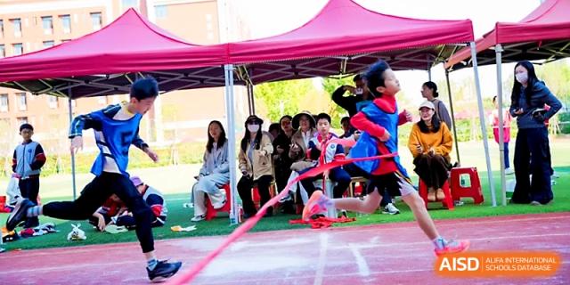 A student sprints through a pink ribbon at the finish line of a race during a sports day at Wuhan Guanggu Future School.