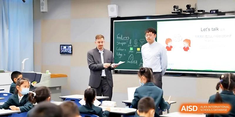 Two instructors lead an interactive group discussion with students in a well-equipped, contemporary classroom at Yung Wing School Zhuhai.