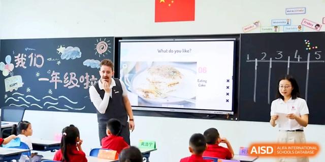 A teacher presents a lesson on a digital smartboard to attentive students sitting at their desks at Yung Wing School Zhuhai.