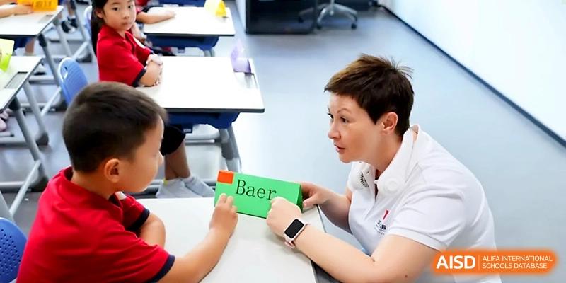 A female teacher works one-on-one with a student using colorful letter blocks for language learning at Yung Wing School Zhuhai.
