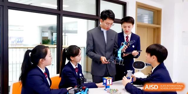 Students and a teacher collaborate on a complex robotics project with mechanical parts in a STEM lab at Yung Wing School Zhuhai.