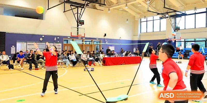 Students participate in a traditional bamboo dance activity during a cultural event in the gymnasium at Yung Wing School Zhuhai.