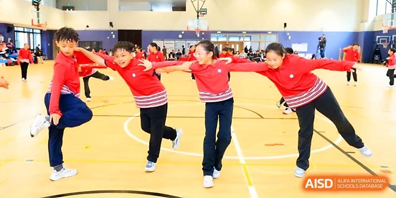 A line of students in red shirts hold hands and run together during a spirited team-building event at Yung Wing School Zhuhai.