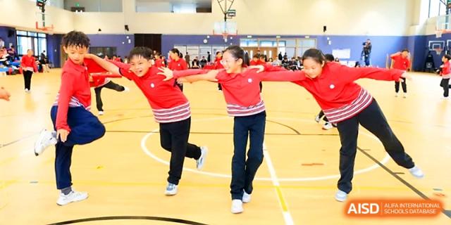 A line of students in red shirts hold hands and run together during a spirited team-building event at Yung Wing School Zhuhai.