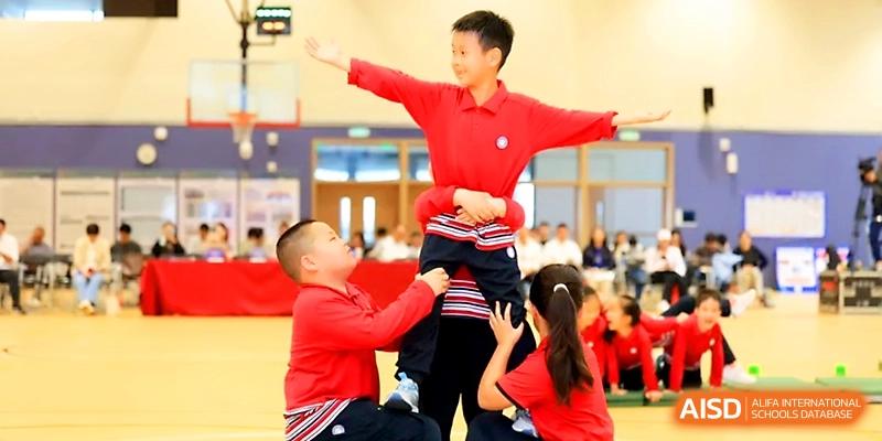 A group of students in red uniforms perform a coordinated acrobatic stunt during a sports exhibition at Yung Wing School Zhuhai.