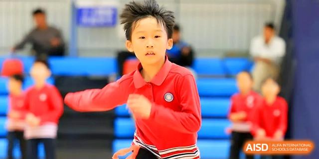 A young boy in a red athletic shirt focuses while running during a physical education class at Yung Wing School Zhuhai.