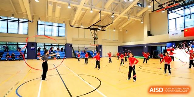 Students participate in various fitness stations across the large indoor basketball court at Yung Wing School Zhuhai.