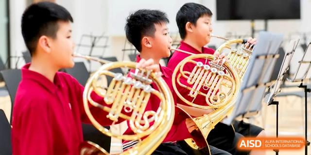 Two young boys in the school band hold their brass French horns during a musical performance at Yung Wing School Zhuhai.