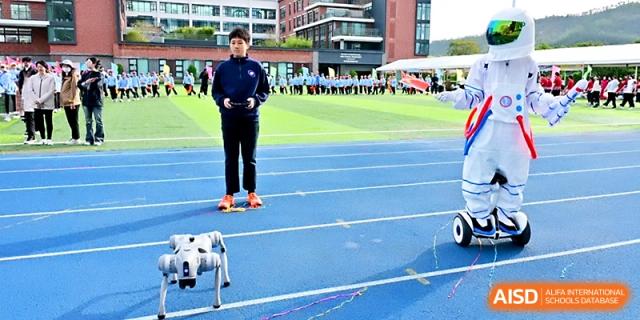 A student demonstrates a robotic dog on the blue outdoor track during a technology showcase at Yung Wing School Zhuhai.