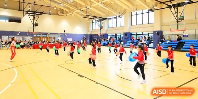 A wide view of students active in the brightly lit indoor sports complex during a physical education day at Yung Wing School Zhuhai.