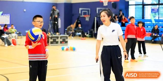 A female coach instructs a student on the indoor court during a sports training session at Yung Wing School Zhuhai.