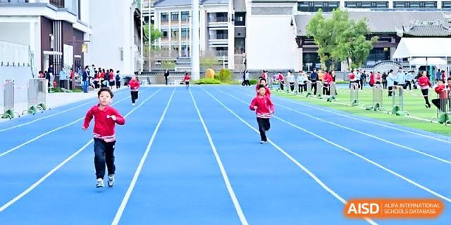 A young girl sprints down the blue running lane during a competitive track event at Yung Wing School Zhuhai.