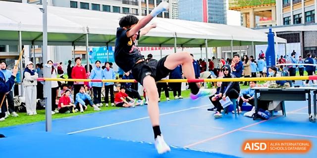 A student athlete successfully clears the high jump bar during an outdoor track and field competition at Yung Wing School Zhuhai.