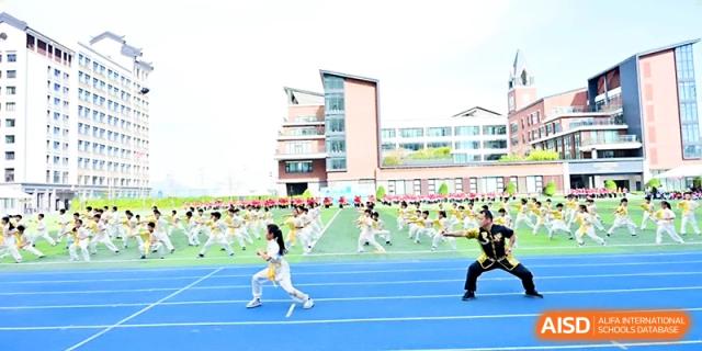 Students perform a synchronized martial arts routine on the blue track and green field during a showcase at Yung Wing School Zhuhai.