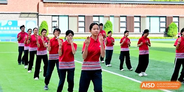 Female students in red and white striped shirts perform a graceful synchronized dance on the school grounds at Yung Wing School Zhuhai.
