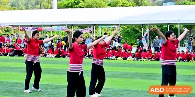 Two students in red shirts lead a group dance performance during an outdoor cultural event at Yung Wing School Zhuhai.