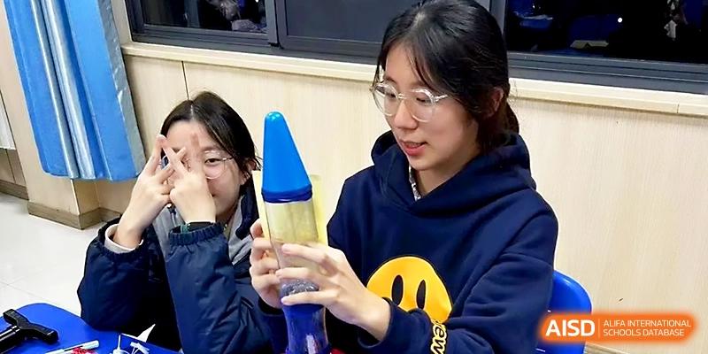 Two female students observe a blue lava lamp during a science experiment in a classroom at Zhangjiagang Foreign Language School.