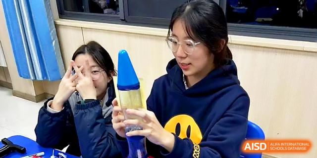 Two female students observe a blue lava lamp during a science experiment in a classroom at Zhangjiagang Foreign Language School.