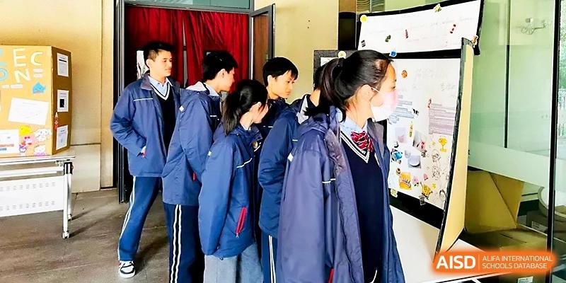 A group of students in blue uniforms gather around a table for a collaborative science activity at Zhangjiagang Foreign Language School.