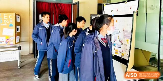 A group of students in blue uniforms gather around a table for a collaborative science activity at Zhangjiagang Foreign Language School.