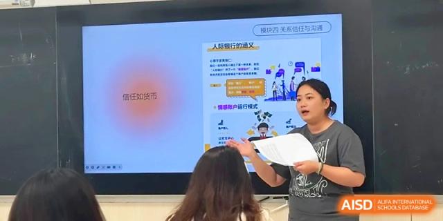 A teacher points to a detailed infographic on an interactive screen during a classroom presentation at Zhangjiagang Foreign Language School.