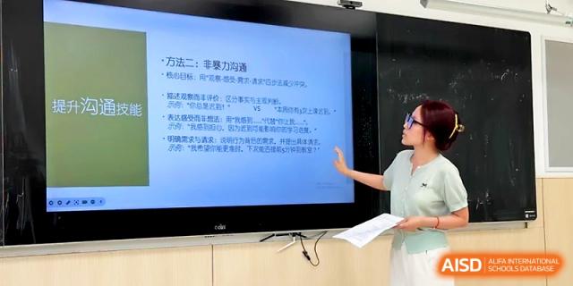 A female instructor explains educational material shown on a large digital display to her students at Zhangjiagang Foreign Language School.