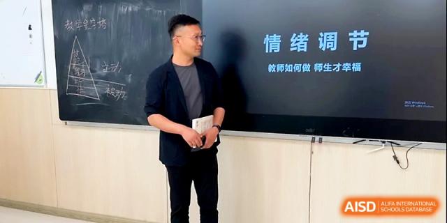 A male instructor stands before a digital screen during a training session or meeting at Zhangjiagang Foreign Language School.