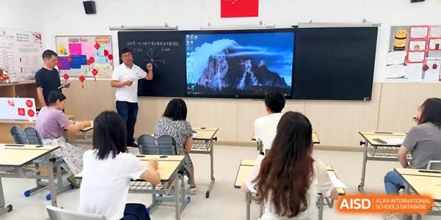 A teacher stands by a digital screen showing a nature scene while students watch from their desks at Zhangjiagang Foreign Language School.