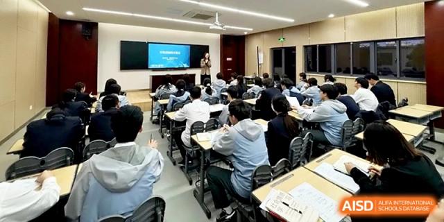 A wide shot of a classroom filled with students attending a lecture using a large digital display at Zhangjiagang Foreign Language School.