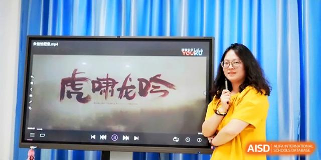 A teacher stands next to a screen displaying Chinese characters during a language or culture lesson at Zhangjiagang Foreign Language School.