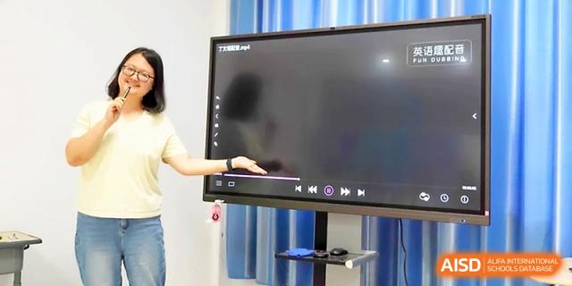 A female educator points to a video screen while explaining a lesson to her students at Zhangjiagang Foreign Language School.