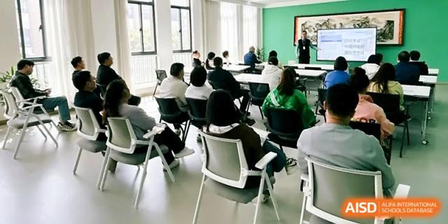 An audience of attendees sits in a modern lecture hall, watching a presentation on a screen at Zhangjiagang Foreign Language School.