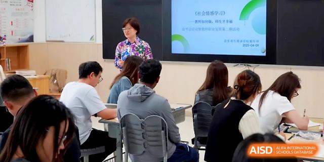 A female lecturer in a floral shirt presents to a focused group during an educational workshop at Zhangjiagang Foreign Language School.