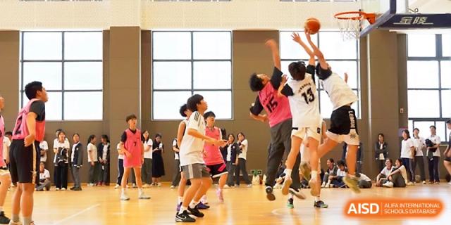 Competitive basketball players jump for a rebound during a high-energy game in the gymnasium at Zhangjiagang Foreign Language School.