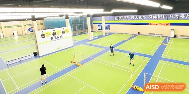 An overhead view shows students playing badminton on green indoor courts during a physical education class at Zhangjiagang Foreign Language School.