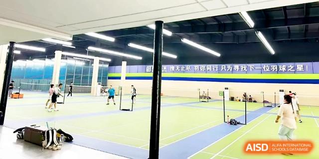 A wide shot of the indoor sports facility shows multiple badminton games happening simultaneously at Zhangjiagang Foreign Language School.