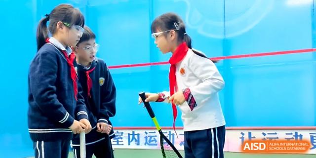 Two students wearing red scarves prepare their sports equipment for an upcoming match at Zhangjiagang Foreign Language School.