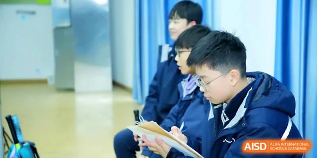 A row of students sits on the sidelines, carefully taking notes during a sports event at Zhangjiagang Foreign Language School.