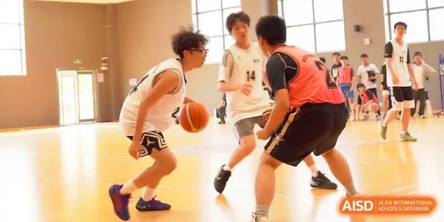 Two basketball players face off as one dribbles the ball during a competitive school match at Zhangjiagang Foreign Language School.
