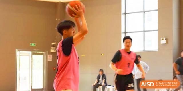 A student in a pink jersey focuses on the hoop while preparing to take a shot during a basketball game at Zhangjiagang Foreign Language School.
