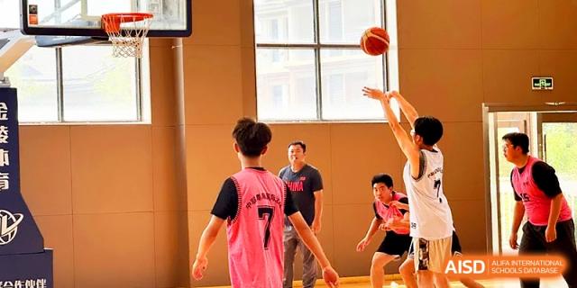 A student in a pink jersey watches the ball fly toward the hoop during an indoor basketball session at Zhangjiagang Foreign Language School.
