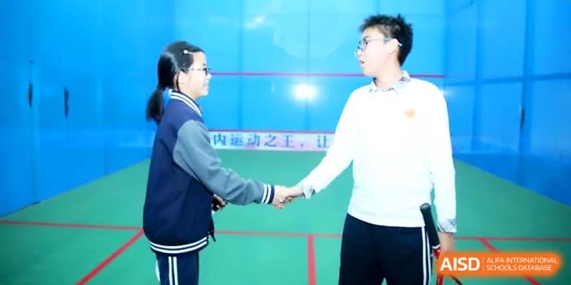 Two students in school uniforms shake hands across a net after finishing a sports match at Zhangjiagang Foreign Language School.