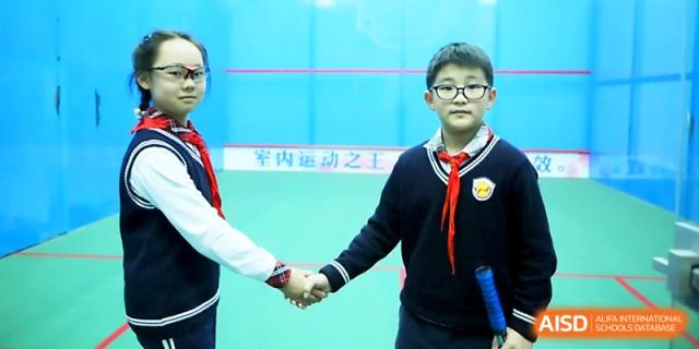 Two young students in red scarves shake hands in a show of good sportsmanship on the court at Zhangjiagang Foreign Language School.