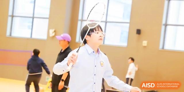 A student focused on the game holds a badminton racket high while playing in the school gym at Zhangjiagang Foreign Language School.