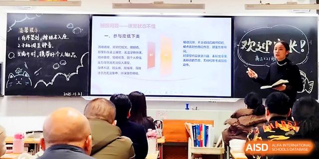 A digital display shows a detailed educational presentation while students take notes in the foreground at Zhengzhou No.19 High School.